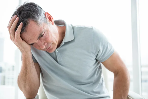 Tensed man sitting against window