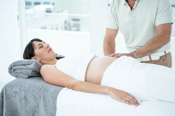 Pregnant woman receiving a stomach massage