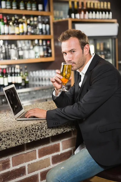 Man using laptop computer and drinking a beer
