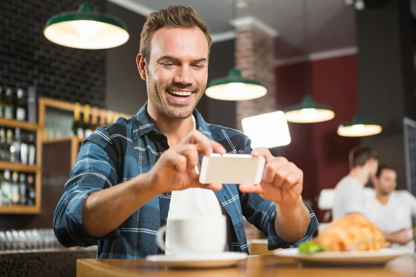 Handsome man taking a picture of his sandwich