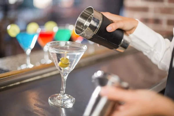 Hand pouring a cocktail in a bar