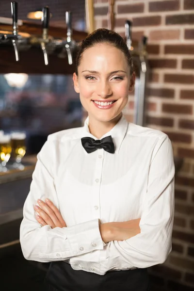 Smiling barmaid with arms crossed