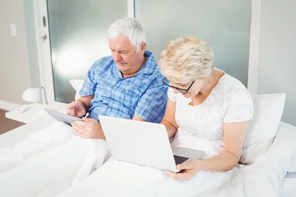 Senior couple using technologies on bed