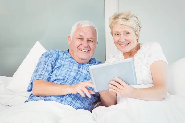 Senior couple using tablet on bed