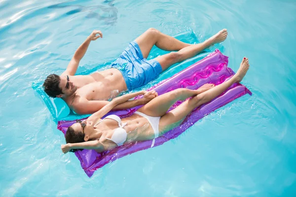 Couple relaxing on inflatable rafts