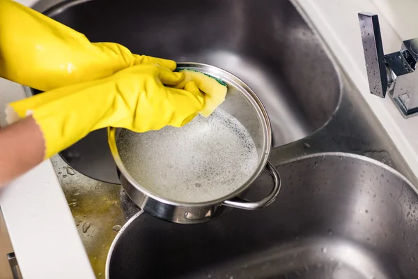 Woman wearing gloves washing utensils