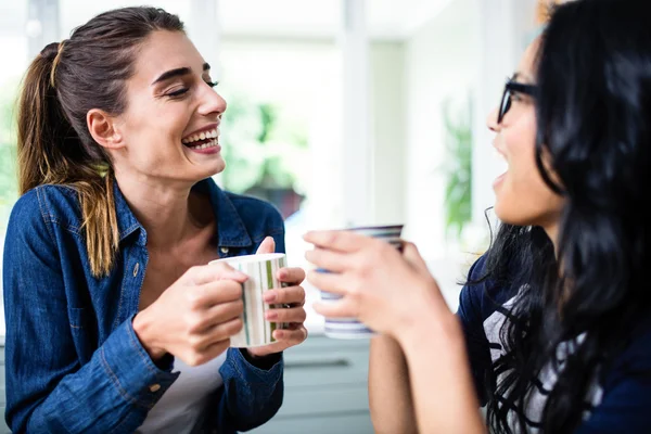 Friends laughing while drinking coffee