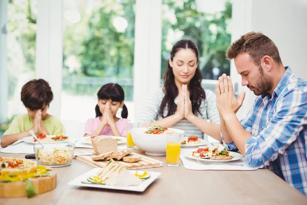 Family praying while sitting at table