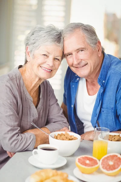 Smiling senior couple at table with breakfast