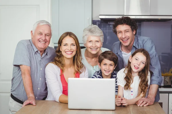 Smiling family with laptop in kitchen