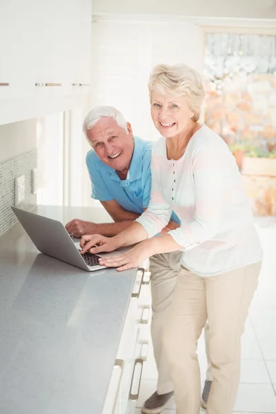 Portrait of senior couple using laptop in kitchen