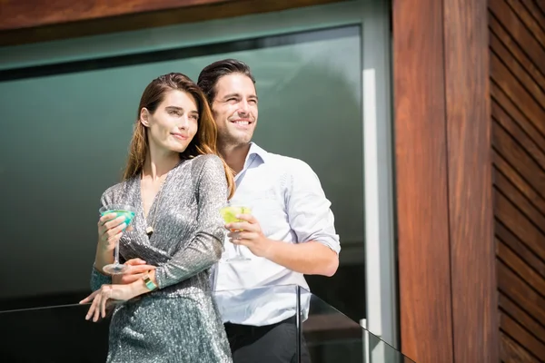 Couple with drinks standing in balcony