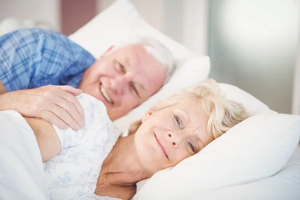 Senior woman relaxing besides man on bed