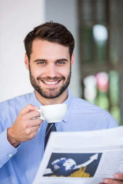 Businessman holding coffee cup and newspaper