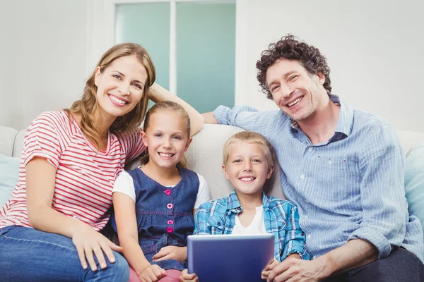 Family with digital tablet sitting on sofa