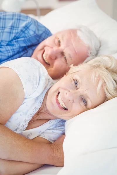 Portrait of happy senior couple lying on bed