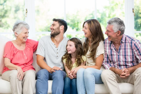 Family laughing while sitting on sofa