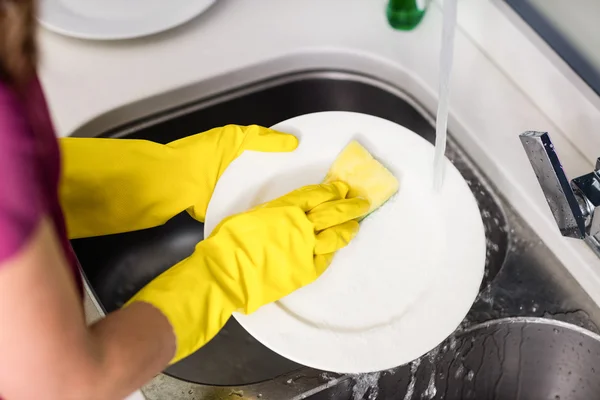 Woman washing plate at washbasin