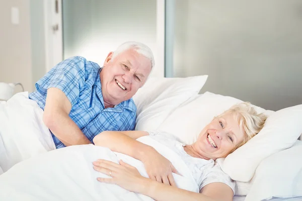 Portrait of happy senior couple relaxing on bed