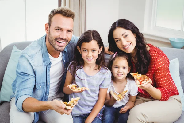 Family eating pizza on sofa