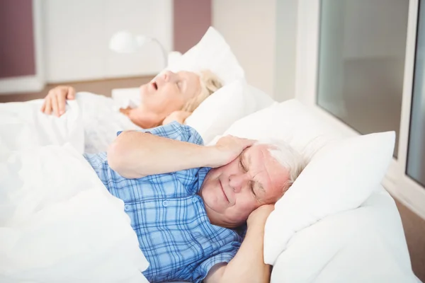 Man covering ears from snoring wife