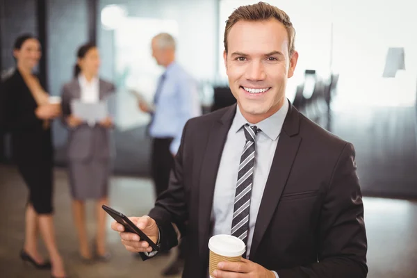 Businessman holding phone and cup of coffee