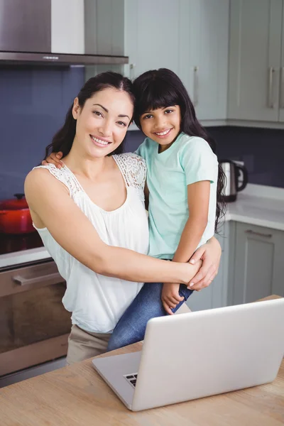 Mother carrying daughter with laptop