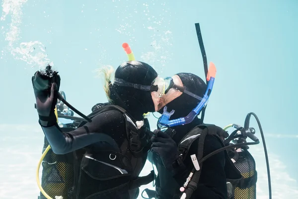 Couple kissing underwater while scuba diving