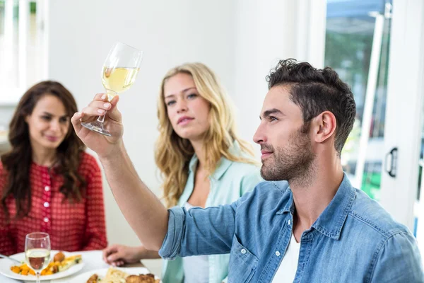 Smiling man holding white wine glass with friends