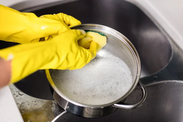 Woman wearing gloves washing utensils