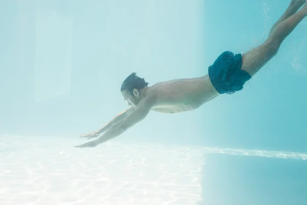 Shirtless man swimming under swimming pool