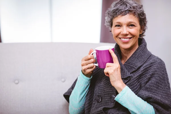 Woman with coffee mug sitting on sofa