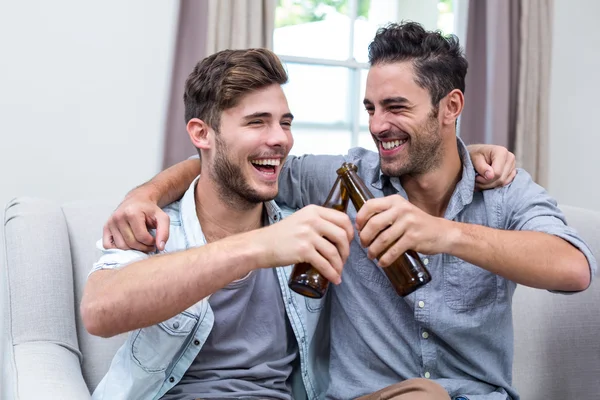 Male friends toasting beer at home