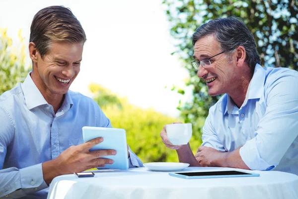 Two businessmen meeting in a restaurant using tablet