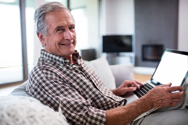 Portrait of senior man using laptop in living room