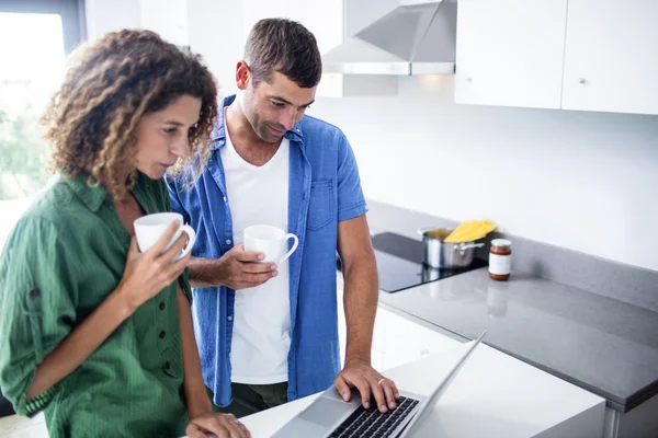 Couple using laptop while having a cup of coffee