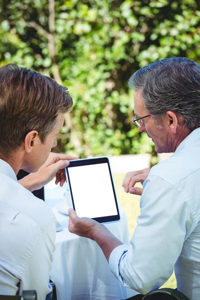 Two businessmen meeting in a restaurant using tablet