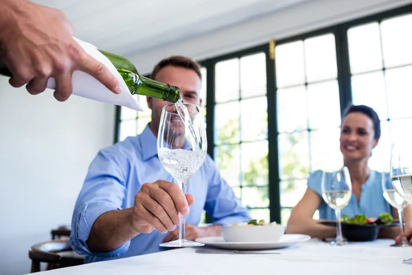 Waiter serving wine to group of friends