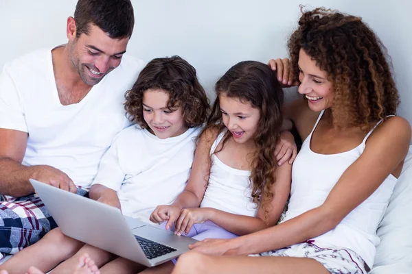 Family using laptop together on bed