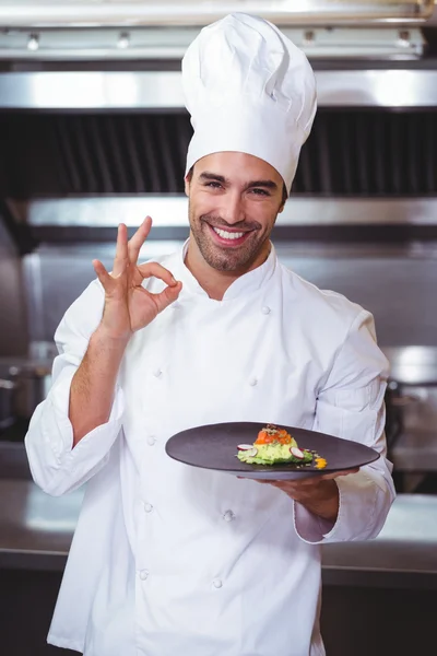 Male chef holding plate and doing ok sign
