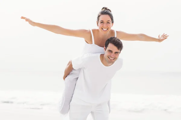 Man giving a piggy back to woman on the beach