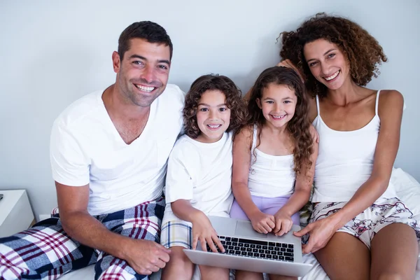 Portrait of family using laptop together on bed