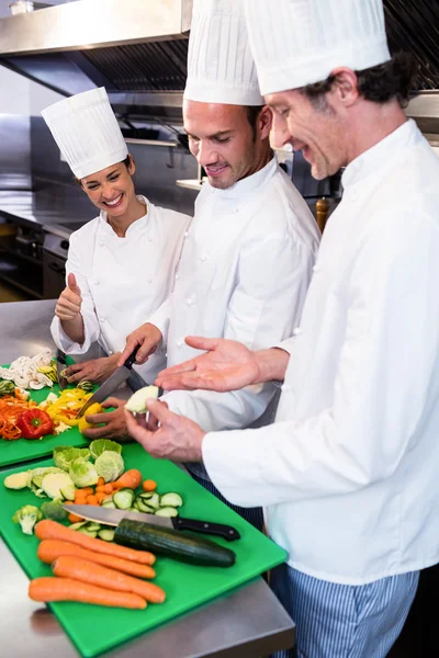 Chef teaching colleagues to slice vegetables