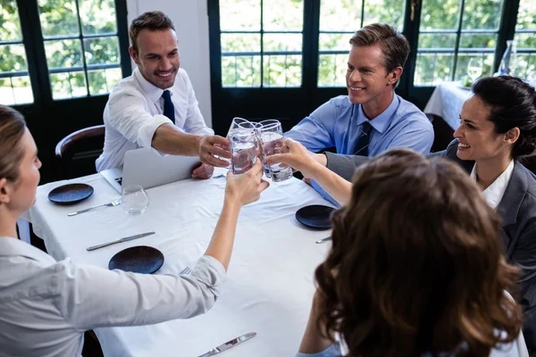 Businesspeople toasting glasses of water in restaurant