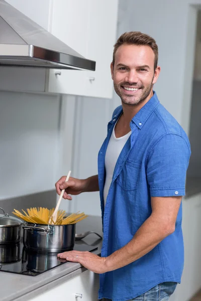 Young man cooking spaghetti