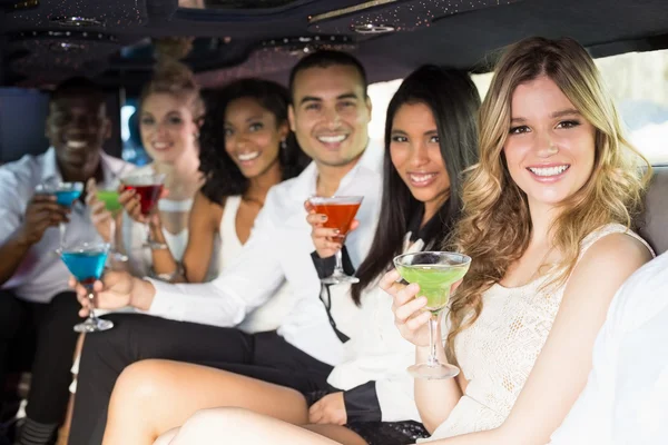 Well dressed people drinking cocktails in a limousine