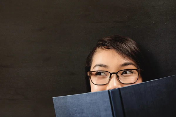 Student hiding face behind book