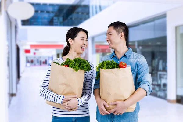 Couple looking at each other while holding grocery bags