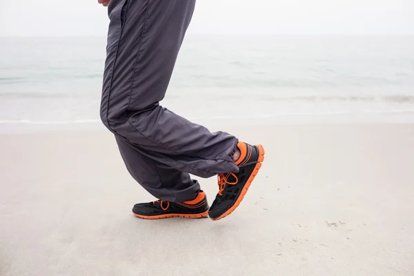 Man's foot while jogging on beach