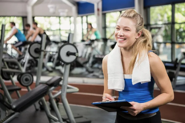 Female gym instructor writing on clipboard